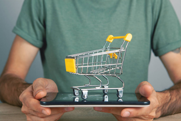 holding a tablet with a shopping basket - Фото, зображення