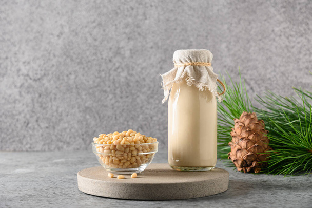 Vegan cedar nut milk in bottle on gray background. Alternative milk. Healthy vegan drink. - Fotó, kép