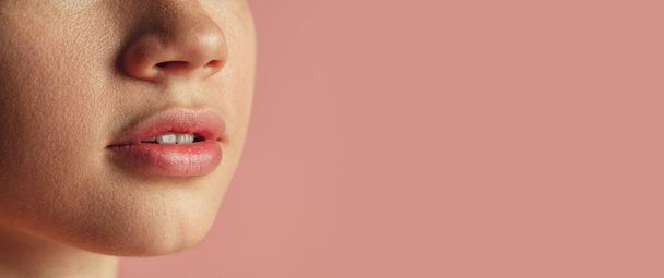 Rajatut naisen kasvot muotokuva vaaleanpunainen tausta. Kaunis luonnollinen huulet - Valokuva, kuva