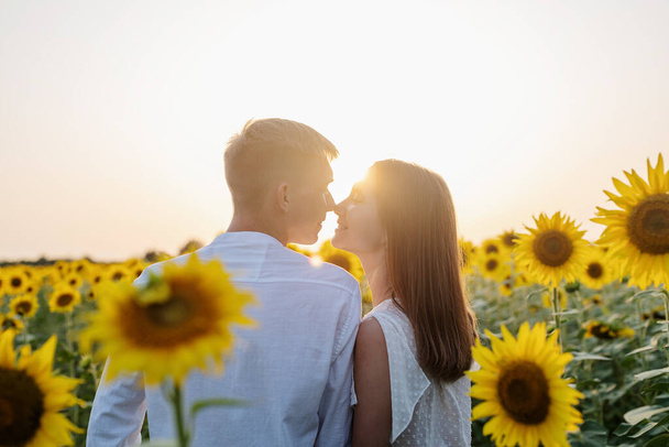 Autumn nature. Young romantic couple walking in sunflower field in sunset - Foto, Imagen