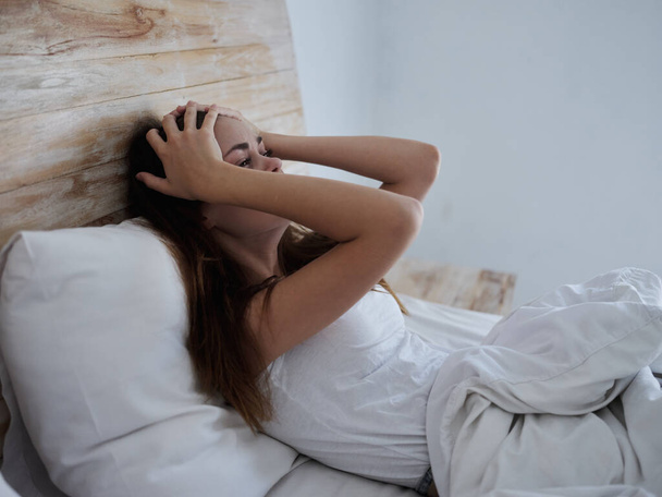 mulher com temperatura deitada na cama mãos na cabeça emoções - Foto, Imagem