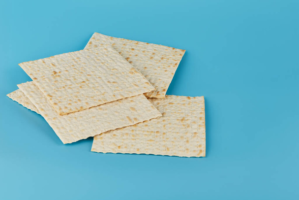 Traditional Jewish matzah for the religious holiday of Passover casually lies in a bunch on a blue background. - Fotoğraf, Görsel
