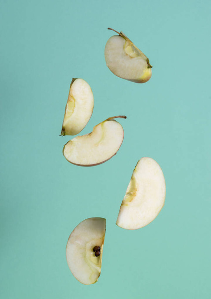Slices of ripe apples hang in the air. Green background in the background - Photo, Image