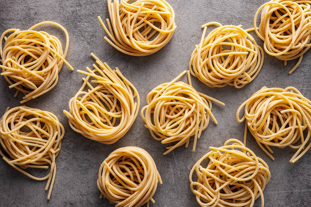 Italian pasta nest. Uncooked spaghetti nest on kitchen table. Top view. - Photo, Image