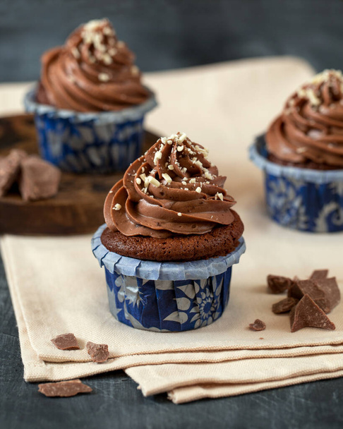 Schokoladen-Cupcake aus nächster Nähe. Makrofotografie in der Food-Fotografie. Schokoladenstücke. Süßes Dessert. Käsecreme. Bäckerei - Foto, Bild