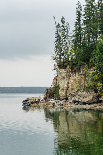 wooded river bank with crumbling marble cliffs, water erosion of coastal rocks - Foto, immagini