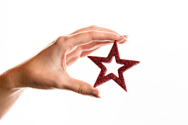 A closeup shot of a hand holding a star decoration isolated on a white background - Foto, Bild