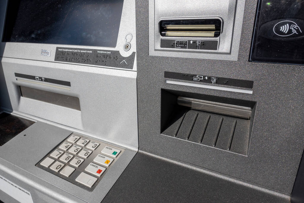 Hoekige weergave van een ATM-nummer pin pad en check deposit slot bij een outdoor machine buiten een bank. - Foto, afbeelding