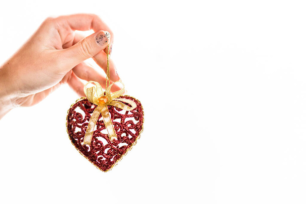 A closeup shot of a hand holding a heart ornament isolated on a white background - Φωτογραφία, εικόνα