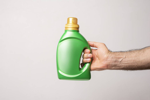 A male hand holding a green kitchen detergent bottle with copy space isolated on white background - Foto, imagen