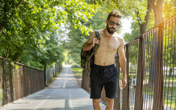 Елегантний атлетичний чоловік з бородою і голий торсо повертається з вуличного тренування
. - Фото, зображення