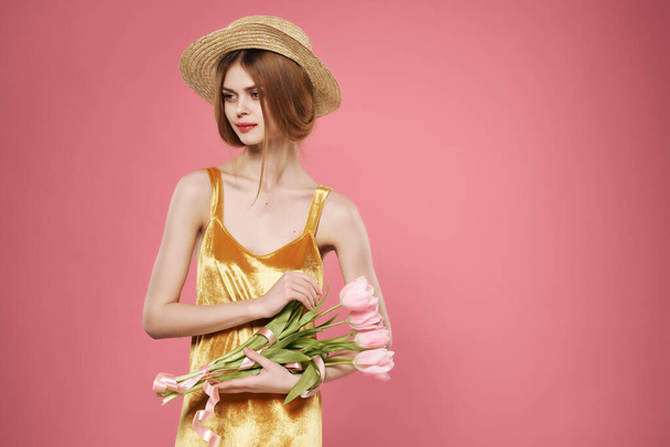 γυναίκα με μπουκέτο λουλούδια στο καπέλο πολυτέλεια ρομαντισμό μόδας ροζ φόντο - Φωτογραφία, εικόνα