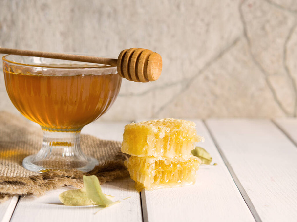 Le miel coule d'une trempette à miel dans un beau bol en verre. Gros plan. Miel épais bio sain et peignes. - Photo, image