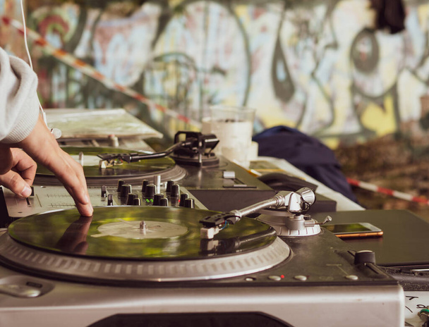 DJ zenél egy hip-hop partin. analóg lemezjátszó, Dj lemezjátszót és keverőt használ a vakaráshoz. - Fotó, kép