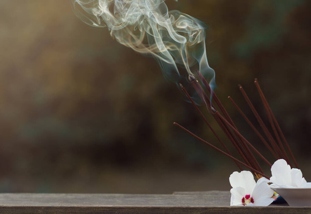 Many incense sticks were lit to perform Buddhist rituals Smoke from large quantities of incense and white flowers for Buddhist rituals, religious ceremonies in the open air. Copy space. - Foto, afbeelding