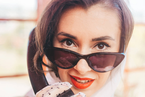 gyönyörű fiatal nő boldogan beszél telefonon egy angol stílusú piros telefonfülkében. Egy lány fehér ruhában és szemüvegben. Felvétel. közelkép. - Fotó, kép
