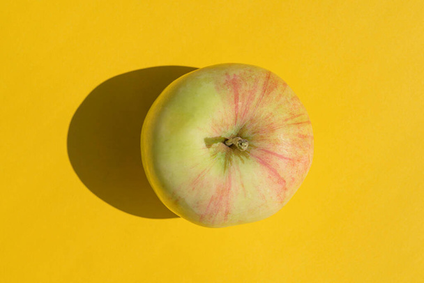 egy kemény árnyalatú alma sárga alapon - Fotó, kép