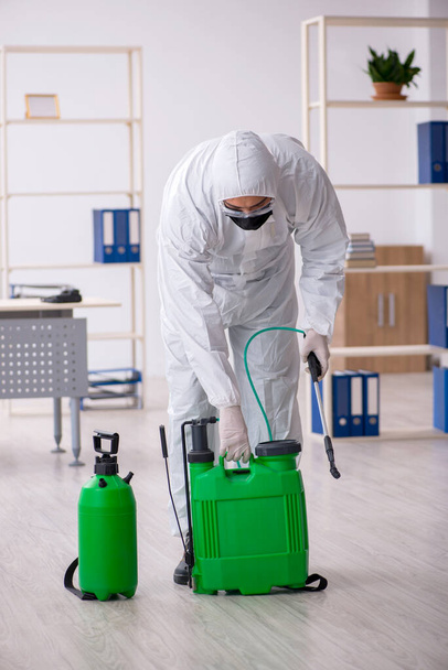 Junger Mann desinfiziert Büro während Pandemie - Foto, Bild