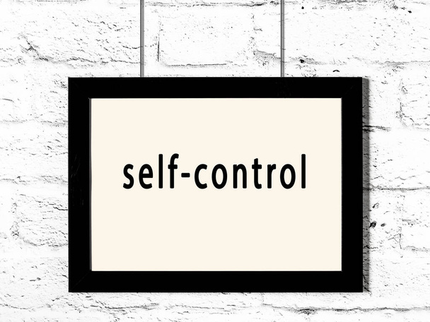 Black wooden frame with inscription self-control hanging on white brick wall  - Foto, Imagem