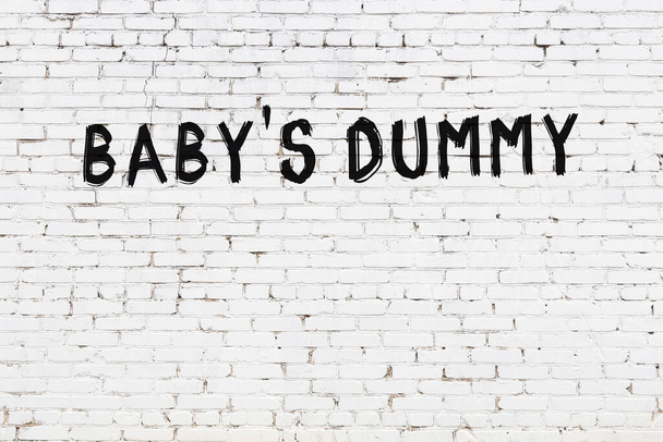 Opschrift baby 's dummy geschreven met zwarte verf op witte bakstenen muur. - Foto, afbeelding