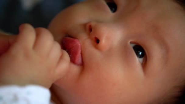 Cerca de la cara de lindo niño de Asia tumbado en la cama y poner el dedo en la boca - Metraje, vídeo
