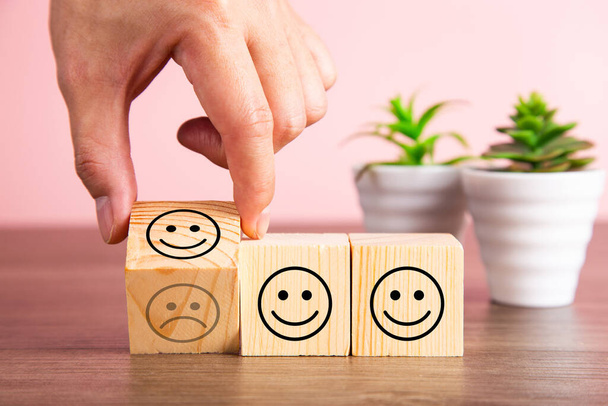 Customer service evaluation and satisfaction survey concepts. The client's hand turned the happy face smile on wooden blocks, copy space - Photo, Image