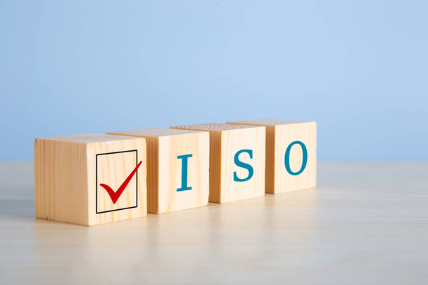 L'abbreviazione ISO su cubi di legno con segno di spunta su sfondo blu. Concetto di approvazione della certificazione di controllo qualità ISO. - Foto, immagini