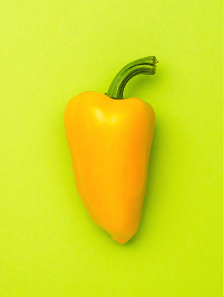Large ripe yellow bell pepper on a green background. Vegetarian food. A fresh crop of vegetables. - Fotó, kép