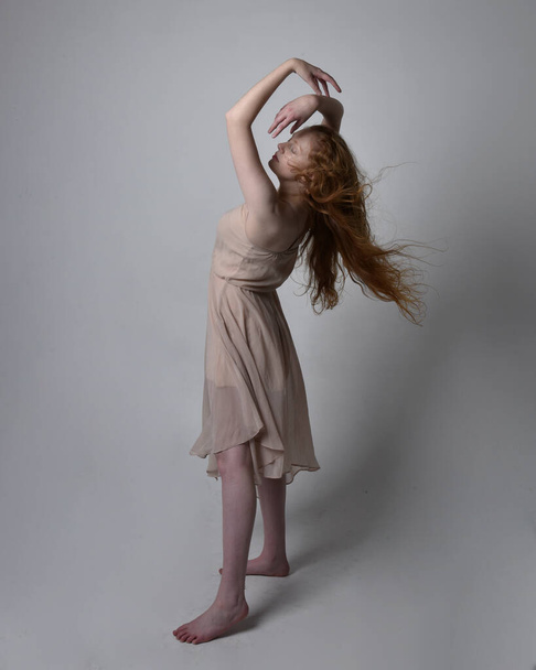Retrato de cuerpo entero de una bailarina pelirroja bonita, con piel tonificada vestido de hada que fluye. Posturas gestuales de pie aisladas sobre fondo de estudio. - Foto, Imagen