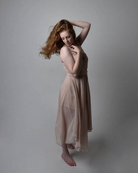 Retrato de comprimento total de dançarina mulher de cabelos vermelhos bonita, vestindo pele tonificada vestido de fada fluindo. Em pé poses gestuais isoladas no fundo do estúdio. - Foto, Imagem