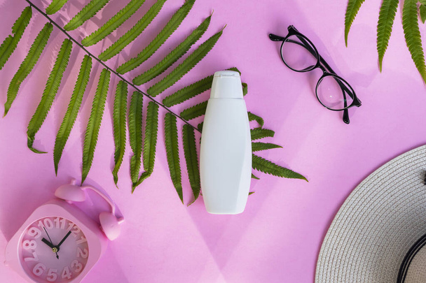 Botella cosmética blanca sobre fondo de papel rosa. Concepto de producto de belleza orgánica natural, estilo minimalista de verano - Foto, imagen