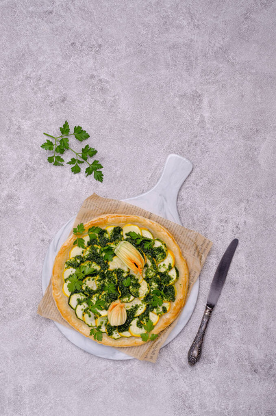 Round vegetable pie with green sauce on a concrete background. Top view. Selective focus. - Foto, afbeelding