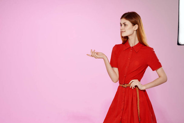vörös hajú nő piros ruha kéz gesztusok luxus rózsaszín háttér - Fotó, kép
