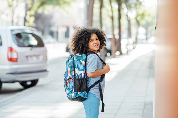 Afro handsome boy walks with his backpack in the park after school - Photo, Image