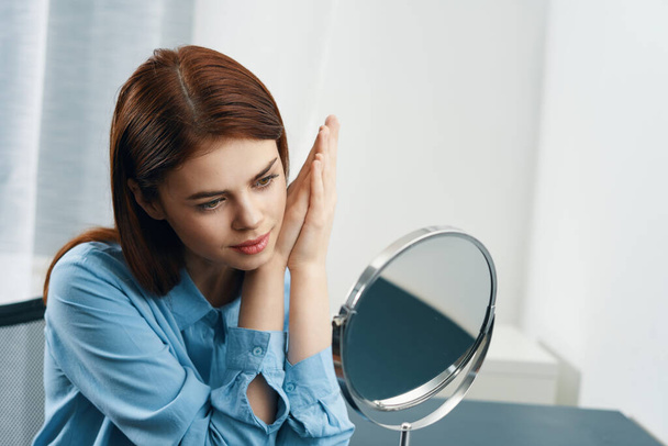 женщина смотрит в зеркало прическа косметика утром чистая кожа - Фото, изображение