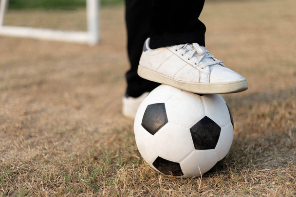 Esportes e recreação uma bola parada por um pé usando um tênis branco no campo de futebol. - Foto, Imagem