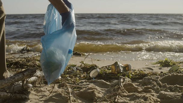Eco volunteer cleaning beach, collecting trash in bag, wildlife preservation - Foto, Imagem