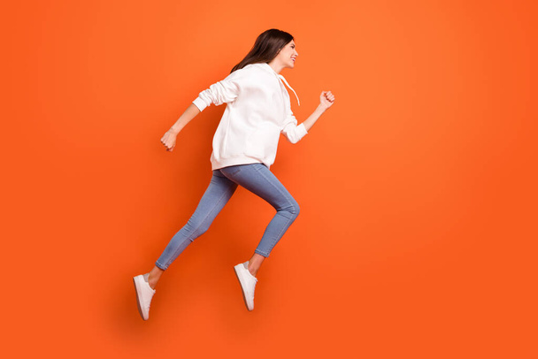 Full length body size profile side view of pretty motivated cheerful girl jumping running isolated bright orange color background - Fotó, kép