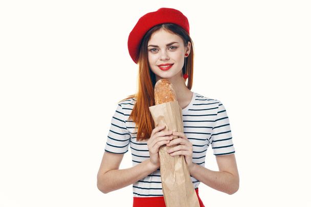 γυναίκα με κόκκινο καπέλο με ένα γαλλικό καρβέλι στα χέρια της ένα σνακ Gourmet τρόπο ζωής - Φωτογραφία, εικόνα