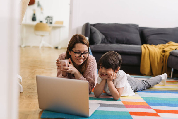 mother and child laying on floor and using laptop computer at home - Φωτογραφία, εικόνα