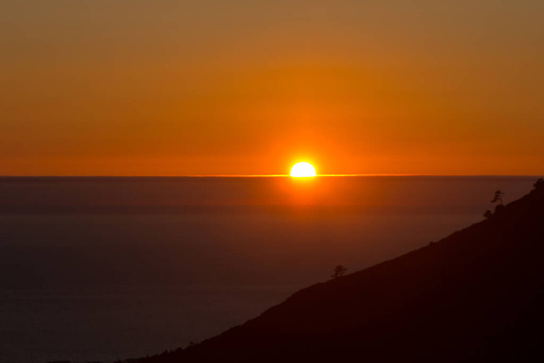 Помаранчевий тон під час заходу сонця над Атлантичним океаном, Галісія, Іспанія, перед річкою Ароза. Захід - це напрямок, в якому заходить сонце.. - Фото, зображення