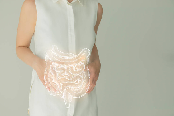 Unrecognizable female patient in white clothes, highlighted handrawn intestine in hands. Human digestive system issues concept. - Фото, изображение
