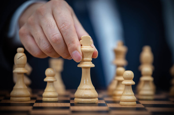 Ein Geschäftsmann im Anzug hält einen Schachkönig in der Hand. - Foto, Bild