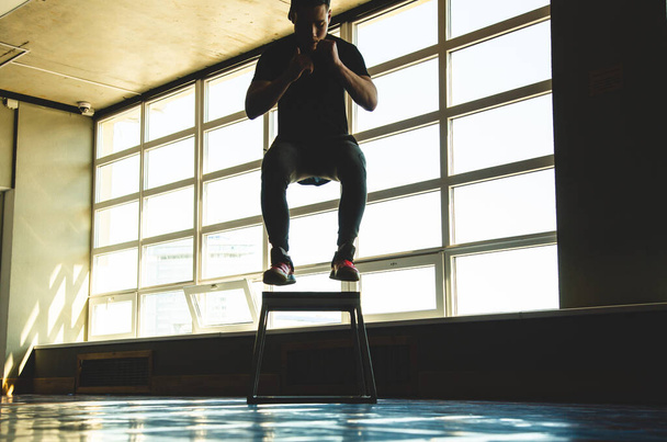sports man jumps on a special platform in the gym opposite the window. Crossfit silhouette shot - Fotó, kép