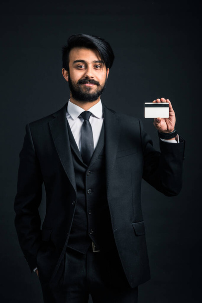 Portrait of a young handsome successful Indian in a classic black three-piece business suit on a dark background - Photo, image