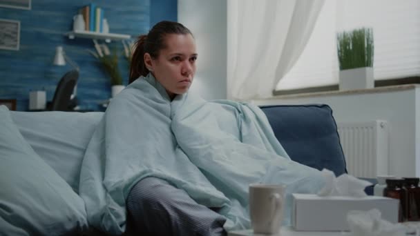 Sick woman with seasonal flu shivering in blanket at home - Footage, Video