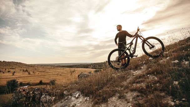 Man with bicycle standing on hill - Foto, Imagen