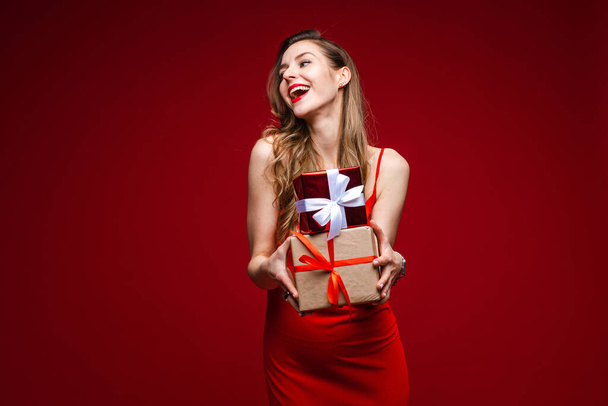 Gyönyörű nő ajándékok piros háttér. - Fotó, kép