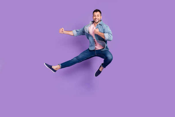 Πλήρες μήκος σώματος μέγεθος φωτογραφία άνθρωπος χαμογελώντας πηδώντας επάνω σε καράτε κατάρτισης απομονωμένο παστέλ βιολετί φόντο χρώμα - Φωτογραφία, εικόνα