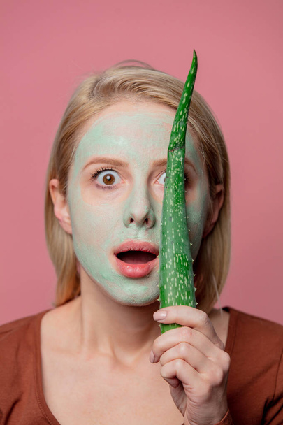 schönes blondes Mädchen mit grüner Maske und Aloe-Zweig - Foto, Bild